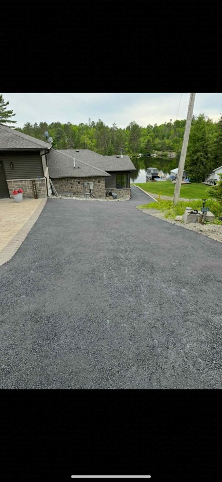 A large black asphalt driveway stretches out, providing a smooth surface for vehicles.