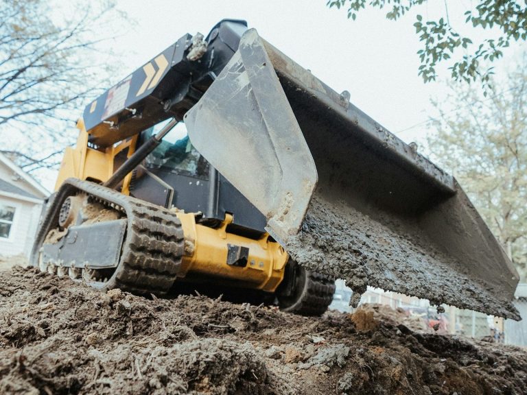 A yellow and black construction vehicle is actively digging into the dirt at a construction site.