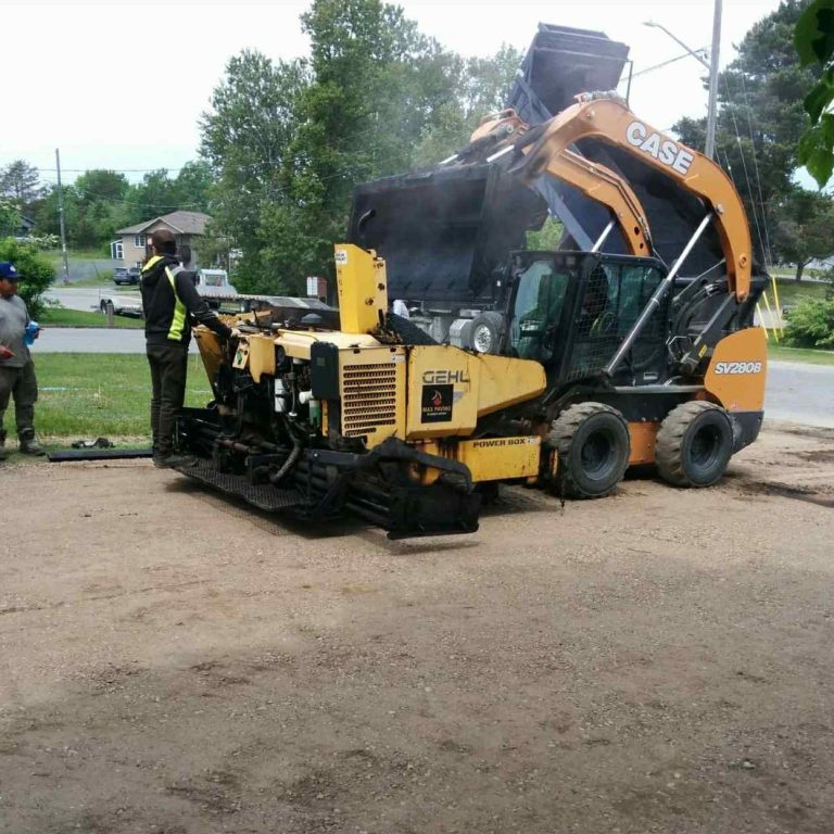 A man operates a construction machine on a worksite, focused on his task amidst construction materials.