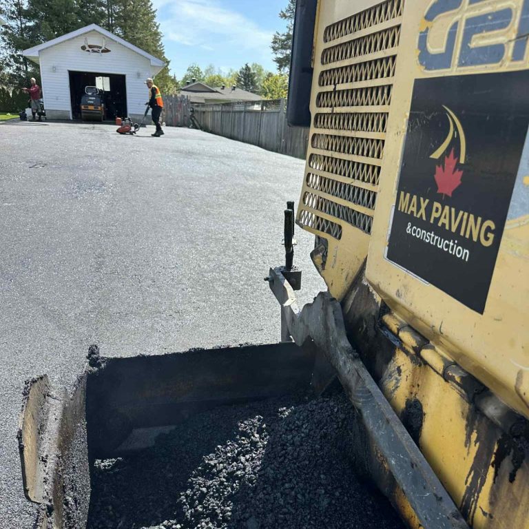 A man operates a paving machine while working on a driveway.