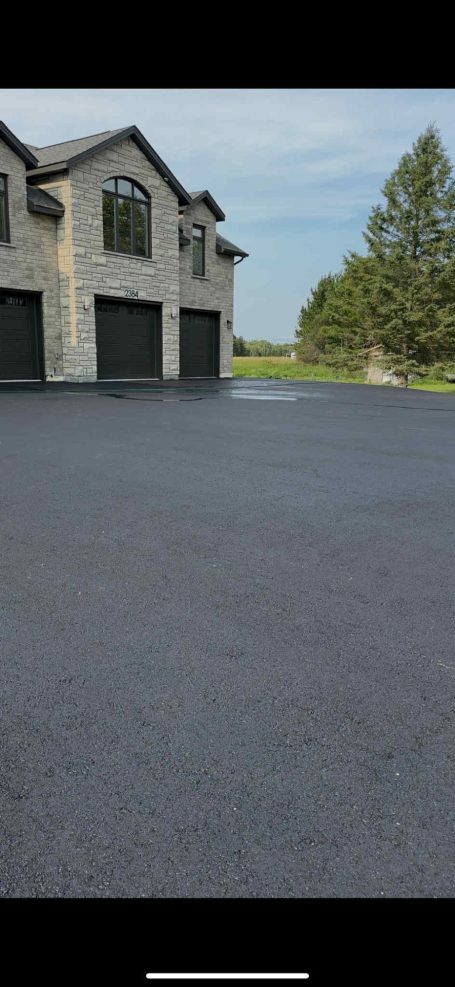 A large garage with a spacious driveway leading up to it, surrounded by greenery.